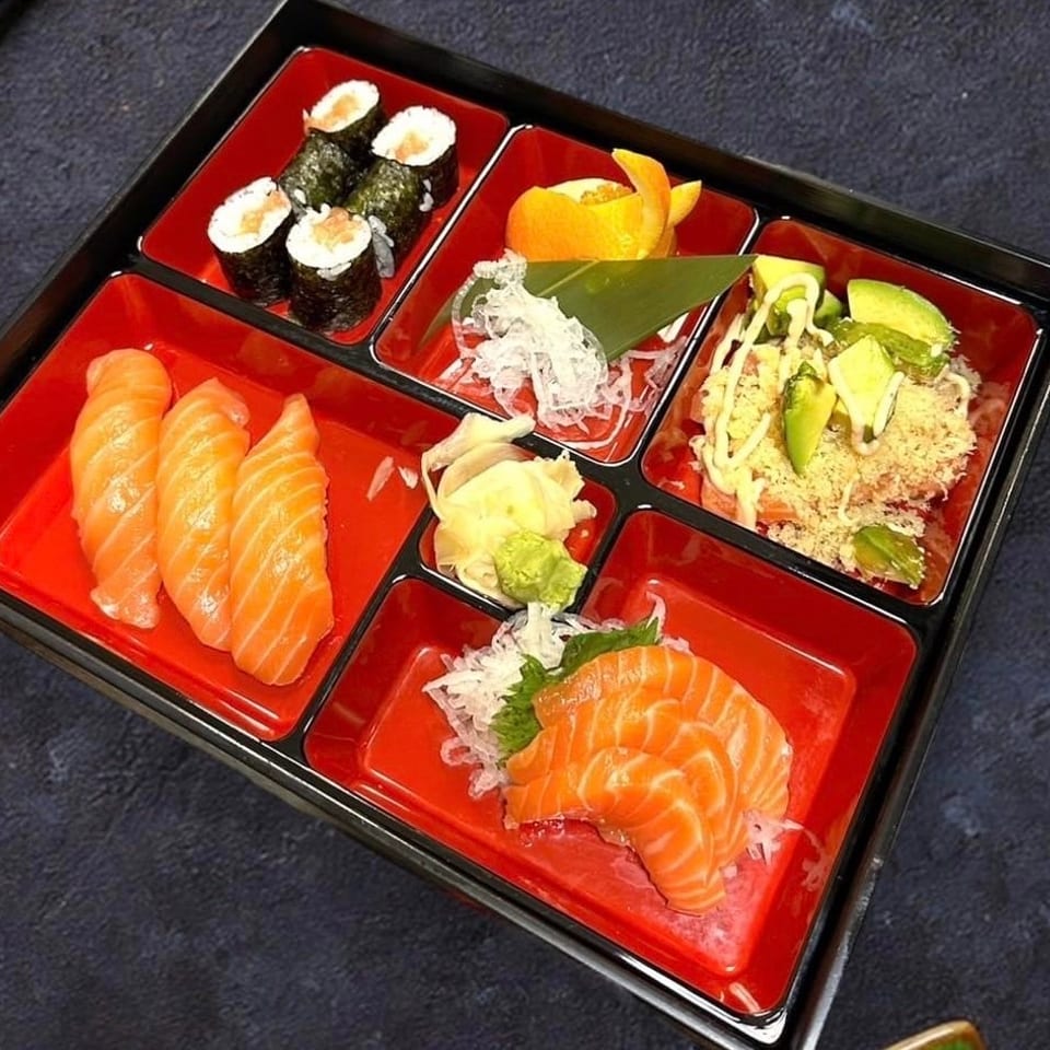 Japanese sushi platter featuring salmon nigiri, maki rolls, sashimi, avocado-topped sushi, pickled ginger, and wasabi.